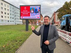 OB Tobias Schick vor einer Werbetafel in der Karl-Marx-Straße. 